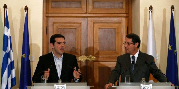 Greek Prime Minister Alexis Tsipras, left, speaks to the media as Cyprus' president Nicos Anastasiades listens during a press conference after their meeting at the Presidential Palace in the capital Nicosia, Monday, Feb. 2, 2015. Tsipras is visiting Cyprus, his first trip abroad as prime minister since his election last month. It's customary for all newly-elected Greek prime ministers to conduct their first trip abroad to Cyprus because of the two countries' deep historic ties. (AP Photo/Petros Karadjias)