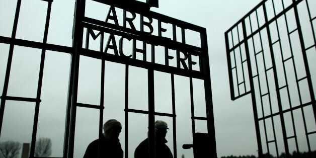 People walk through the gate of the Sachsenhausen Nazi death camp with the phrase 'Arbeit macht frei' (work sets you free) at the eve of the International Holocaust Remembrance Day, in Oranienburg, about 30 kilometers, (18 miles) north of Berlin, Monday, Jan. 26, 2015. The International Holocaust Remembrance Day marks the liberation of the Auschwitz Nazi death camp on Jan. 27, 1945. (AP Photo/Markus Schreiber)