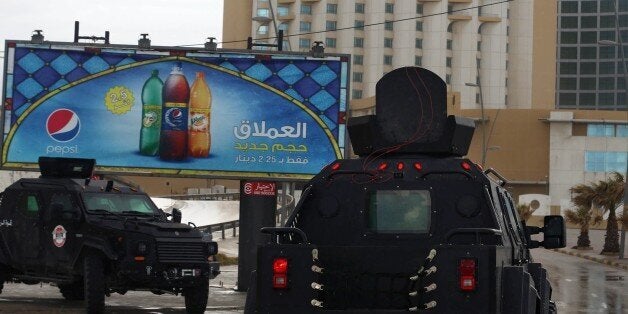 Libyan security forces surround Tripoli's central Corinthia Hotel (R) on January 27, 2015 in the Libyan capital. The hotel was reportedly attacked by Islamist gunmen today and gunfire was heard, an AFP photographer reported. According to security sources at the scene, four armed men had detonated a car bomb in front of the Corinthia Hotel, which is popular with foreigners, killing a guard, before rushing into the hotel. AFP PHOTO/MAHMUD TURKIA (Photo credit should read MAHMUD TURKIA/AFP/Getty Images)