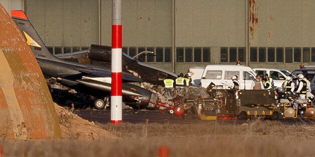 Investigators work around the wreckage of planes the day after a crash at Albacete airbase, Spain, Tuesday, Jan. 27, 2015. The death toll from the crash of a Greek F-16 fighter jet at a Spanish military base during an elite NATO pilot training program rose to 11 Tuesday after a French airmen who suffered serious burns died, Spain's Defense Ministry said. The death came as Spanish investigators probed what caused the jet to lose thrust during takeoff and crash into five parked planes at the Los Llanos air base in southeastern Spain, triggering a series of explosions and a raging fire. (AP Photo/Daniel Ochoa de Olza)