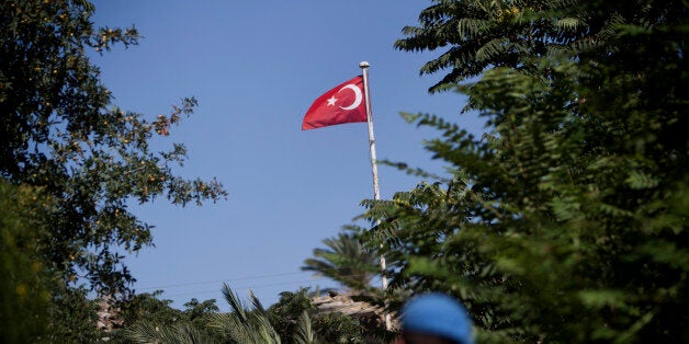 A British UN soldier walks through an alley in the green line, a UN controlled buffer zone, separating the divided Cypriot capital of Nicosia as a Turkish flag flies in the Turkish-controlled northern side on July 4, 2012. AFP PHOTO/BEHROUZ MEHRI (Photo credit should read BEHROUZ MEHRI/AFP/GettyImages)