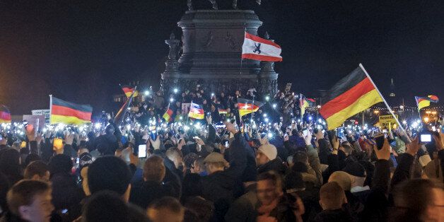 Participants of a rally called 'Patriotic Europeans against the Islamization of the West' (PEGIDA) hold German flags and lights during a demonstration entitled âChristmas With Pegidaâ in front of the bronze equestrian statue of King John of Saxony in Dresden, eastern Germany, Monday, Dec. 22, 2014. For the past ten weeks, activists protesting Germanyâs immigration policy and the spread of Islam in the West have been marching each Monday. (AP Photo/Jens Meyer)