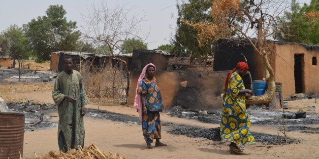 Villagers walk through razed homes in Mainok, outside Maiduguri, Borno State, Nigeria, on March 6, 2014. At least 74 people were killed in attacks on March 1, 2014 in villages near Maiduguri, blamed on Boko Haram militants, taking the overall death toll this year beyond 300, with no apparent end in sight to the carnage. Gunmen dressed in military fatigues and armed with powerful assault rifles, rocket-propelled grenades and explosives laid siege to the village of Mainok, killing 39. AFP PHOTO