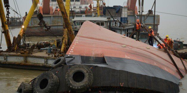 Members of a rescue team (orange) look at a section of the hull (front) of a tugboat which sank on a trial voyage in Jingjiang, east China's Jiangsu province on January 16, 2015. More than 20 people were missing on January 16, including foreigners, after a tugboat sank on a trial voyage in China's vast Yangtze river, state media and authorities said. CHINA OUT AFP PHOTO (Photo credit should read STR/AFP/Getty Images)