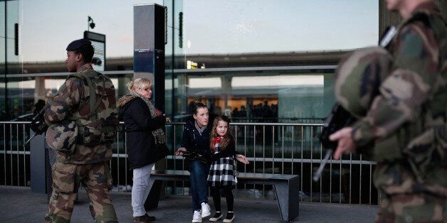 A young girl looks on at French soldiers patrolling at the Roissy Charles de Gaulle airport, in Roissy, north of Paris, Saturday, Jan. 17, 2015. France ordered 10,000 troops into the streets Monday to protect sensitive sites â nearly half of them to guard Jewish schools â as it hunted for accomplices to the Islamic militants who left 17 people dead as they terrorized the nation. (AP Photo/Thibault Camus)