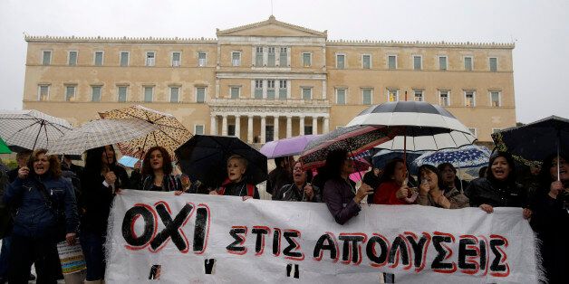 Employees of the Finance Ministry shout slogans as they hold a banner reading ''No to Layoffs'' during a rally outside the Greek Parliament in Athens, Wednesday, Nov. 6, 2013. Services across Greece shut down Wednesday as unions held a 24-hour general strike to protest further austerity cuts in the cash-strapped country. (AP Photo/Thanassis Stavrakis)