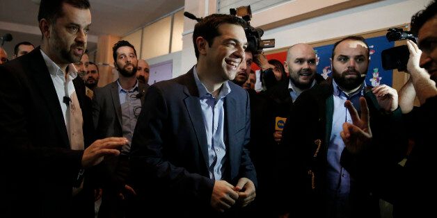 Alexis Tsipras, center, leader of Greece's Syriza left-wing main opposition party smiles as he arrives to vote at a polling station in Athens, Sunday, Jan. 25, 2015. Greeks were voting Sunday in an early general election crucial for the country's financial future, with the radical left Syriza party of Alexis Tsipras tipped as the favorite to win, although possibly without a large enough majority to form a government. (AP Photo/Petros Giannakouris)