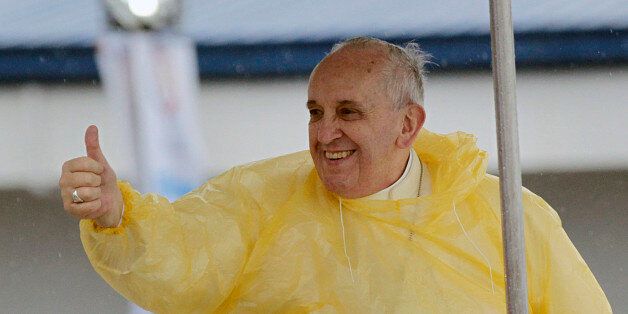 Wearing a yellow raincoat, Pope Francis gives a thumbs up to the faithful as he arrives in Tacloban, Philippines, Saturday, Jan. 17, 2015. A rain-drenched but lively crowd wearing yellow and white raincoats welcomed Pope Francis in the typhoon-ravage central Philippine city of Tacloban early Saturday, chanting