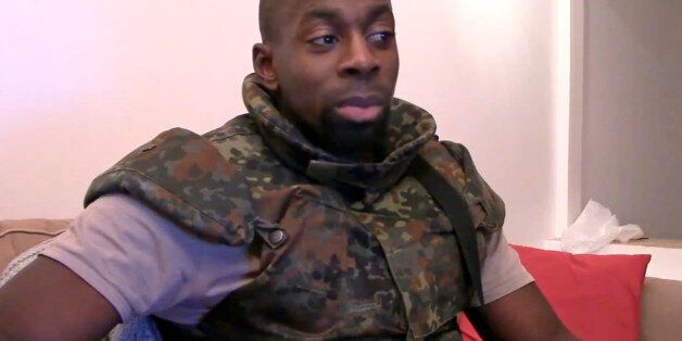 AP CANNOT INDEPENDENTLY VERIFY THE CONTENT, DATE, LOCATION OR AUTHENTICITY OF THIS MATERIAL IN THIS IMAGE - This image made from a video posted online by militants on Sunday, Jan. 11, 2015, shows slain hostage-taker Amedy Coulibaly, who shot a policewoman and four hostages at a kosher grocery in Paris, speaking in broken Arabic that he seems to be reading from a paper, in front of an Islamic State emblem, as he defends the attacks carried out on the satirical newspaper Charlie Hebdo, police and the Jewish store. At one point, Coulibaly says Charlie Hebdo will be attacked