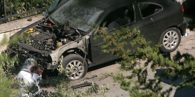 A police investigator photographs evidence next to a damaged car, following an explosion near the home of Greek Culture Minister Giorgos Voulgarakis, in central Athens, on Tuesday, May 30, 2006. No one was hurt in the blast which damaged several parked cars.(AP Photo/Petros Giannakouris)