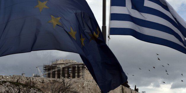 A Greek and an EU flag wave in front of the ancient temple of Parthenon atop the Acropolis hill in Athens on January 13, 2015. Greece could exit the euro by accident, Finance Minister Gikas Hardouvelis said Wednesday in a new warning of what could happen if anti-austerity leftist party Syriza wins the election later this month. AFP PHOTO / ARIS MESSINIS (Photo credit should read ARIS MESSINIS/AFP/Getty Images)