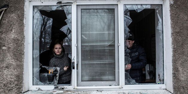 A Ukrainian woman looks through a broken window at their flat after it was hit by Ukrainian Artillery in the Voroshilovsky area, center of Donetsk, Ukraine. Sunday, Jan. 18, 2015. The separatist stronghold, Donetsk, was shaken by intense outgoing and incoming artillery fire as a bitter battle raged for control over the city's airport. Streets in the city, which was home to 1 million people before unrest erupted in spring, were completely deserted and the windows of apartments in the center rattled from incessant rocket and mortar fire. (AP Photo/Manu Brabo)