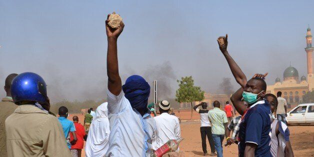 People holds rocks as they demonstrate against French weekly Charlie Hebdo's publication of a cartoon of the Prophet Mohammed near the grand mosque in Niamey, on January 17, 2015. At least 1,000 youths assembled at the grand mosque in the capital Niamey, some of them throwing rocks at police while others burned tyres and chanted 'Allahu Akbar' ('God is Greatest'). The protest came a day after a policeman and three civilians were killed and 45 injured in protests against Charlie Hebdo in Niger's second city of Zinder, which saw three churches ransacked and the French cultural centre burned down.AFP PHOTO / BOUREIMA HAMA (Photo credit should read BOUREIMA HAMA/AFP/Getty Images)