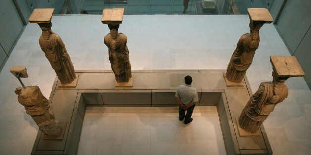 A visitor to the new Acropolis museum stands behind the Caryatids, female figures used instead of pillars, in Athens on Sunday, June 21, 2009. The empty space in front of the visitor denotes the absence of a Caryatid now on display at the British Museum in London. The Acropolis Museum opened its gates today to the first visitors who came to see the more than 4,000 exhibits on display, including those parts of Parthenon's marble frieze not held by the British Museum. (AP Photo/Thanassis Stavrakis)