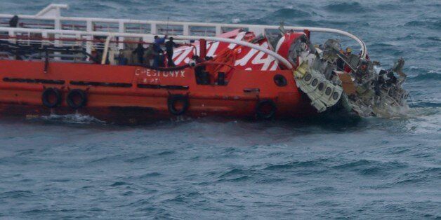 Members of an Indonesian search and rescue team pull wreckage from AirAsia flight QZ8501 onto the Crest Onyx ship at sea on January 10, 2015. Indonesia said on January 9, 2015 it had found the tail of AirAsia Flight QZ8501, potentially marking a major step towards locating the plane's black boxes and helping shed light on what caused it to crash into the sea ten days ago. AFP PHOTO / STR (Photo credit should read STR/AFP/Getty Images)