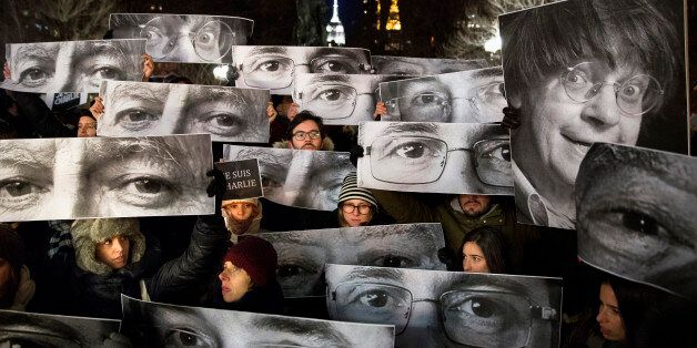 AP10ThingsToSee - Mourners hold signs depicting victim's eyes during a rally in support of Charlie Hebdo, a French satirical weekly newspaper that fell victim to an terrorist attack, Wednesday, Jan. 7, 2015, at Union Square in New York. French officials said 12 people were killed when masked gunmen stormed the Paris offices of the periodical that had caricatured the Prophet Muhammad. (AP Photo/John Minchillo)
