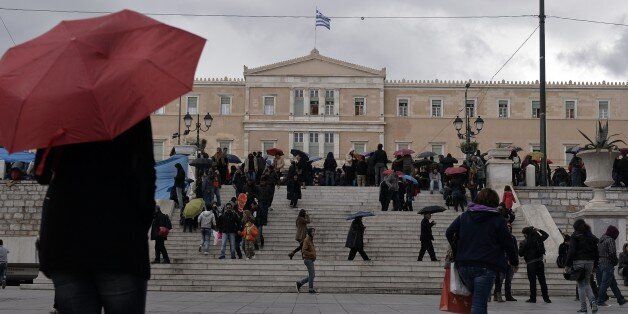People walk in front of the Greek parliament on December 10, 2014. The Greek government unexpectedly brought forward a high-stakes presidential vote, raising fears that a political crisis is looming.The vote by 300 members of parliament to replace President Karolos Papoulias was due in February but a first round has now been set for December 17. The election is a key test for embattled Prime Minister Antonis Samaras, who would be forced to call snap general elections if his candidate -- former EU Environment Commissioner Stavros Dimas -- fails to garner enough support. AFP PHOTO/ LOUISA GOULIAMAKI (Photo credit should read LOUISA GOULIAMAKI/AFP/Getty Images)