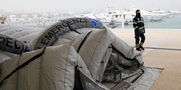 An Italian Red Cross volunteer walks past a tent being set up to accommodate some of the rescued passengers of the 'Norman Atlantic' ferry, in the port of Manfredonia, southern Italy, on December 30, 2014. Ten passengers dead, dozens unaccounted for and no-one able to say with any certainty how many people were on board the Norman Atlantic when it burst into flames. A Greek ferry tragedy in the Adriatic turned into a murder mystery on December 30 as a fiasco over the accuracy of the passenger l