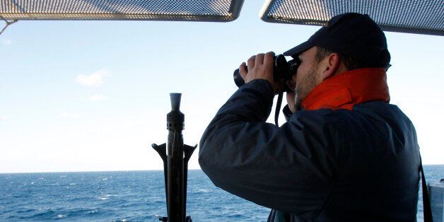 An Italian Navy officer looks through a binocular from the deck Italian Navy San Giorgio ship, during rescue and search operations on the Italian-flagged Norman Atlantic ferry that caught fire in the Adriatic Sea, Tuesday, Dec. 30, 2014. A blaze broke out on the car deck of the Norman Atlantic Sunday, Dec. 28, while the ferry was traveling from the Greek port of Patras to Ancona in Italy causing the death of at least 11 people. Italian and Greek helicopter rescue crews evacuated 427 people among passengers and crew members but Italian officials think the death toll could be much higher because of serious discrepancies in the ship's manifest and confusion over how many people were aboard.