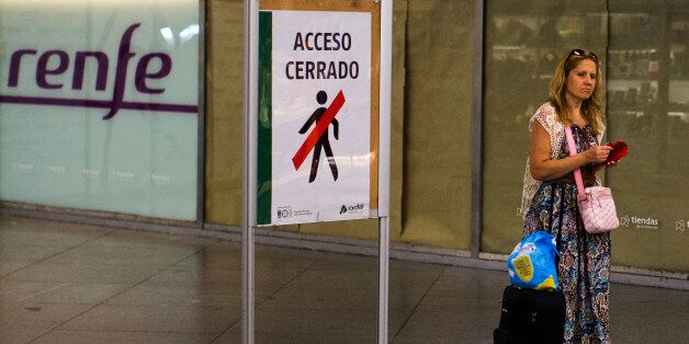 A passenger passes a sign reading 'Closed Access', as she arrives at Atocha train station during a partial train strike, in Madrid, Spain, Thursday, July 31, 2014. Spanish train workers have begun a nationwide strike as one of the country's busiest holiday periods kicks off. Workers for the state train company Renfe and rail infrastructure firm Adif began the strike Thursday to protest staff shortages and company plans to privatize certain operations. (AP Photo/Andres Kudacki)