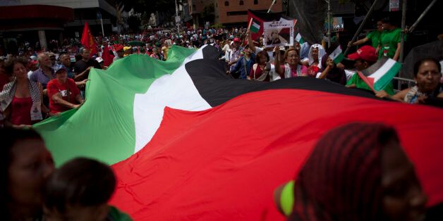 Venezuelans march with a large Palestinian flag during a government organized demonstration in support of the Palestinian people and against Israel's offensive in Gaza, in Caracas, Venezuela, Saturday, Aug. 2, 2014. (AP Photo/Ariana Cubillos)
