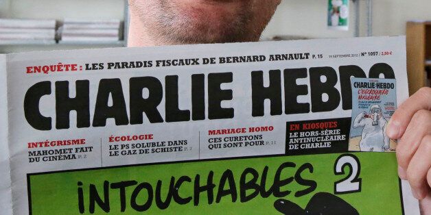 Publishing director of the satyric weekly Charlie Hebdo, Charb, displays the front page of the newspaper as he poses for photographers in Paris, Wednesday, Sept. 19, 2012. Police took up positions outside the Paris offices of the satirical French weekly that published crude caricatures of the Prophet Muhammad on Wednesday that ridicule the film and the furor surrounding it. The provocative weekly, Charlie Hebdo, was firebombed last year after it released a special edition that portrayed the Prophet Muhammad as a