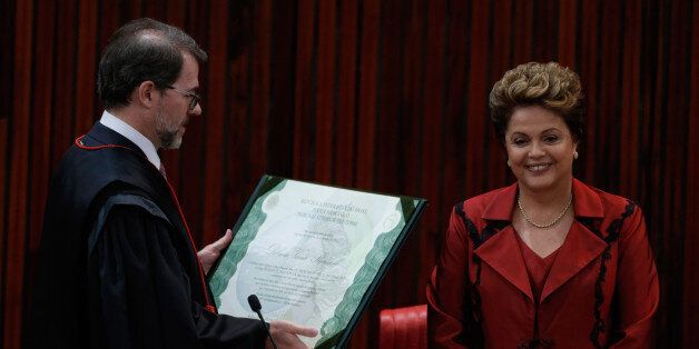 Brazil's President Dilma Rousseff receives a presidential election diploma from the President of the Superior Electoral Tribunal Jose Antonio Dias Toffoli, during a ceremony in Brasilia, Brazil, Thursday, Dec. 18, 2014. Rousseff was re-elected to a second term to lead the world's fifth-largest nation, beating opposition contender Aecio Neves. (AP Photo/Eraldo Peres)