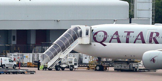 Airport personnel are seen at the foot of the stairs of the Qatar Airways plane that was forced to make an emergency landing at Manchester Airport on August 5, 2014. British police arrested a man suspected of making a hoax bomb threat that forced a Qatar Airways plane to make an emergency landing under military jet escort. AFP PHOTO / LINDSEY PARNABY (Photo credit should read LINDSEY PARNABY/AFP/Getty Images)