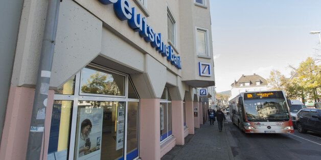 A bus and pedestrians pass a Deutsche Bank AG bank branch in Koenigstein, Germany, on Friday, Oct. 24,...