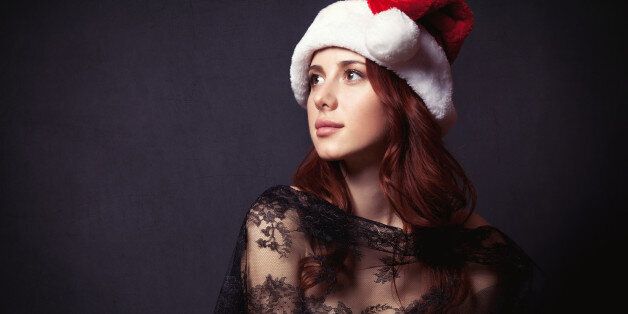 Portrait of a beautiful woman in style dress and Santa Claus hat on dark backgorund