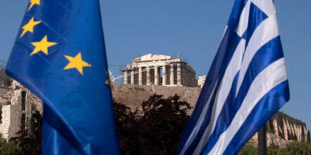 A European Union flag, left, hangs beside a Greek national flag beneath the Parthenon temple on Acropolis hill in Athens, Greece, on Tuesday, May 1, 2012. It is 'entirely possible' IMF, EU will refuse to make next payment to Greece if new govt doesn't fulfill its commitments, UBS's Stephane Deo says in note to clients before May 6 elections. Photographer: Simon Dawson/Bloomberg via Getty Images