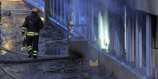 A fireman searches the still smoking debris outside a cellar mosque in Eskilstuna, Sweden, Thursday, Dec. 25, 2014. Five of the twenty at prayer inside were taken to hospital after inhaling smoke when a burning object was hurled through a window, setting fire to the building in the early afternoon. (AP Photo/Pontus Stenberg) SWEDEN OUT