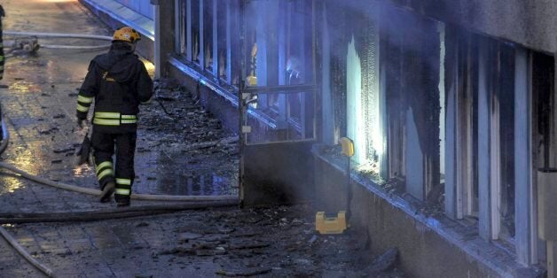 A fireman searches the still smoking debris outside a cellar mosque in Eskilstuna, Sweden, Thursday, Dec. 25, 2014. Five of the twenty at prayer inside were taken to hospital after inhaling smoke when a burning object was hurled through a window, setting fire to the building in the early afternoon. (AP Photo/Pontus Stenberg) SWEDEN OUT