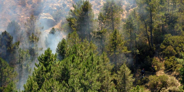 View taken on July 25, 2009 shows firefighters spraying water to protect a forest on fire near the village of Aullene in Corsica. Three fires started on July 23, 2009 in Corsica burning 3.000 hectares of forest. Deadly summer wild fires spread across Spain, France, Italy and Greece with holidaymakers rescued from beaches and thousands of firefighters brought into the battle. AFP PHOTO STEPHAN AGOSTINI (Photo credit should read STEPHAN AGOSTINI/AFP/Getty Images)