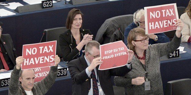Members of the European Parliament hold placards during a voting session on a censure motion on the European Commission on November 27, 2014, in the European Parliament in Strasbourg, eastern France. The European Parliament rejected on November 27 a no confidence motion in Jean-Claude Juncker's European Commission over the 'Luxleaks' tax scandal. In a vote, 101 MEPs approved the censure motion filed by eurosceptic parties, 461 cast their ballots against it and 88 abstained, parliament president Martin Schulz said. AFP PHOTO / FREDERICK FLORIN (Photo credit should read FREDERICK FLORIN/AFP/Getty Images)