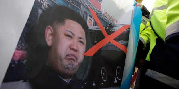 Activists who plan to send anti-North Korea leaflets, hold a defaced image of North Korean leader Kim Jong Un as police officers stand guard during a rally in Paju, north of Seoul, South Korea, Saturday, Oct. 25, 2014. North Korea opened fire on Oct. 10 after activists floated propaganda balloons across the border, following through on a previous threat to attack. (AP Photo/Lee Jin-man)