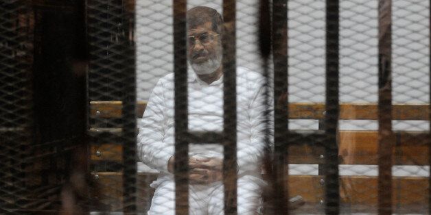 CAIRO, EGYPT - NOVEMBER 5: Ousted Egyptian president Mohammed Morsi looks from behind defendants cage bars during his trial in Cairo, Egypt on November 5, 2014. According to reports, Morsi is standing trial with other defendants from his administration and Muslim Brotherhood for allegedly inciting Islamist supporters to kill anti-Islamist protesters outside the presidential palace in December 2012. (Photo by Stringer/Anadolu Agency/Getty Images)