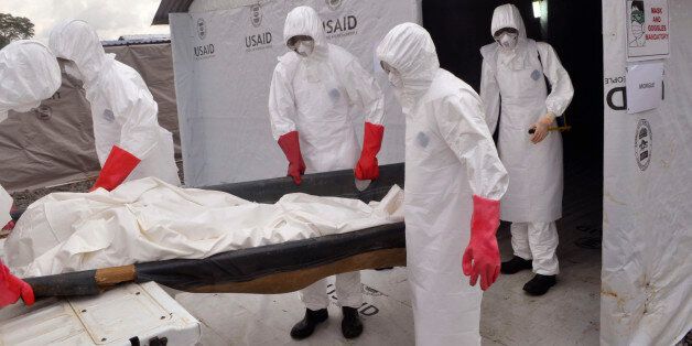 Health workers wearing Ebola protective gear remove the body of a man that they suspect died from the Ebola virus, at a USAID, American aid Ebola treatment center at Tubmanburg on the outskirts of Monrovia, Liberia, Friday, Nov. 28, 2014. The Ebola scare has subsided in the United States, at least temporarily, but the family-owned Kappler Inc. Alabama, USA, manufacturer of protective gear is still trying to catch up with a glut of orders to protect against the disease. (AP Photo/ Abbas Dulleh)