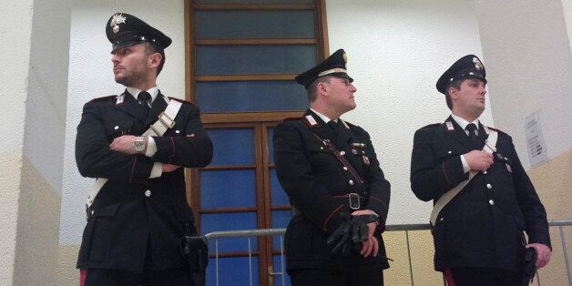 Carabinieri policemen stand in a corridor of the court in Milan, Italy, Thursday, April 10, 2014. A Milan judge says a ruling on how Silvio Berlusconi will serve his tax fraud sentence won't be delivered before next week -- a decision that was raising political tensions in Italy. The judge spent more than an hour in chambers with Berlusconi's lawyers for arguments Thursday on whether Berlusconi will perform community service or be placed under house arrest. The lawyers exited without comment. Whatever the decision, Berlusconi's ability to participate in the upcoming European elections will be severely curtailed -- a point causing unrest in his party. (AP Photo/Antonio Calanni)