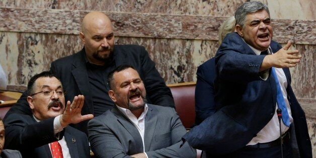 The leader of the far-right political party, Golden Dawn, Nikos Michaloliakos, right, lawmakers Christos Pappas, left, and Yannis Lagos react against Parliament members in Athens, Wednesday, June 4, 2014. Michaloliakos, Pappas, and Lagos were transferred from prison to parliament to speak during a debate on lifting their immunity on additional weapons charges. (AP Photo/Thanassis Stavrakis)