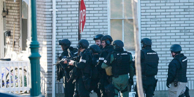 Police gather near a home, Monday, Dec. 15, 2014, in Souderton, Pa., where suspect Bradley William Stone is believed to have barricaded himself inside after shootings at multiple homes. The man killed six people and seriously wounded another in three different homes outside Philadelphia and remained at large hours after the shootings, authorities said Monday. (AP Photo/Matt Rourke)