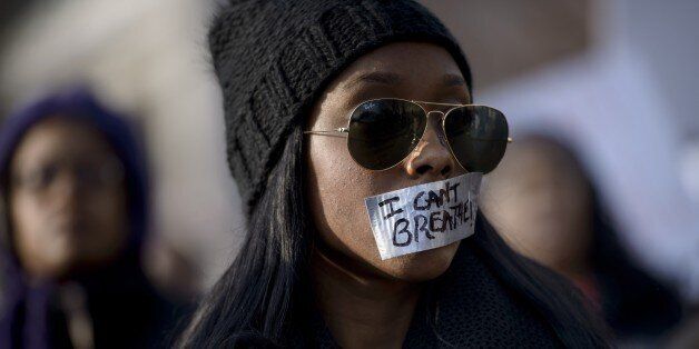 A woman listens to a rally with her mouth taped shut during the 'Justice For All' march December 13, 2014 in Washington, DC. Thousands of people descended on Washington to demand justice Saturday for black men who have died at the hands of white police, the latest in weeks of demonstrations across the United States. AFP PHOTO/BRENDAN SMIALOWSKI (Photo credit should read BRENDAN SMIALOWSKI/AFP/Getty Images)