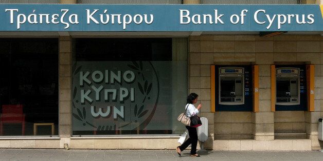 A woman passes outside a branch of Bank of Cyprus in the main shopping street in central capital Nicosia, Cyprus, Sunday, April 14, 2013. Cyprus' President Nicos Anastasiades has chided the central bank chief to not act in ways that