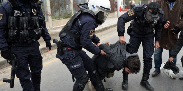 Riot police detain students after they used pepper spray to disperse a protest by dozens of students near Turkish President Recep Tayyip Erdogan's new, contested 1,000-room palace in Ankara, Turkey, Saturday, Nov. 29, 2014. Police used shields and pepper spray to prevent the students from marching to the palace that has become an emblem of Erdogan's increasingly authoritarian style of governing. Video footage showed one officer punching a student in the face as he was being held by another offic