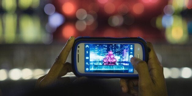 All Logo removed cellular camera phone is used to photograph Giant red ornaments, lights, on display along Sixth Avenue (Avenue of the Americas) in midtown Manhattan for the holiday season in the Manhattan Borough of New York, New York, USA.