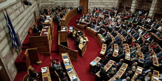 Greek Prime Minister Antonis Samaras, standing at podium, left, speaks to Parliament members during a debate on a confidence vote demanded by the conservative-led governing coalition half-way through its four-year mandate, in Athens on Friday, Oct. 10, 2014. Prime Minister Antonis Samarasâ government is expected to win the vote, but it faces possible early elections soon as it would need opposition support to elect Greeceâs new president in March. (AP Photo/Petros Giannakouris)