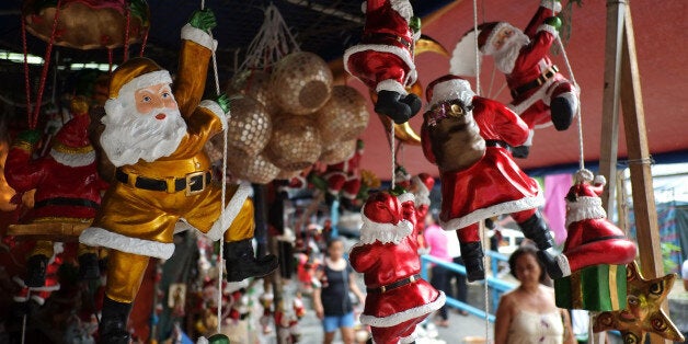 A Filipino woman looks at Santa Claus figurines outside makeshift stalls as people begin shopping for Christmas decorations for their homes in Manila, Philippines, Thursday, Nov. 20, 2014. Christmas is one of the most important holidays in this predominantly Roman Catholic nation. (AP Photo/Aaron Favila)