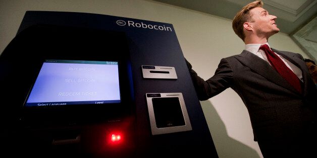 Robocoin CEO Jordan Kelly stands with the Robocoin machine, the world's first bitcoin kiosk (ATM) for buying and selling popular and controversial digital currency, during a demonstration on Capitol Hill in Washington, Tuesday, April 8, 2014. (AP Photo/Pablo Martinez Monsivais)