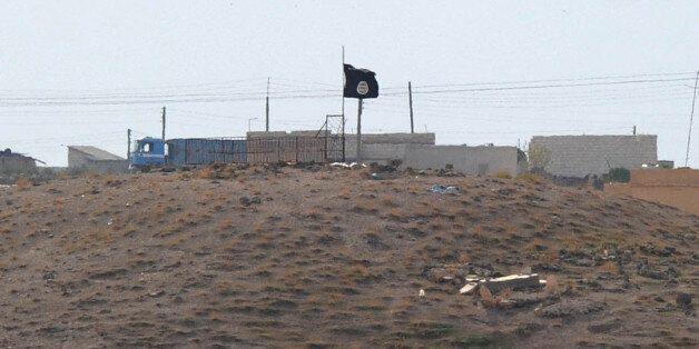 SANLIURFA, TURKEY - OCTOBER 27: A Islamic State (ISIS) black flag flies neasr the Syrian town of Kobani, October 27, 2014 as seen from the Turkish-Syrian border near the southeastern town of Suruc in Sanliurfa province, Turkey. According to a Syrian activist group, the death toll has reached 815 during 40 days of fighting in and around the Syrian town of Kobani and the Britain-based Syrian Observatory for Human Rights reported the death toll for the Islamic State fighters stands at approxima