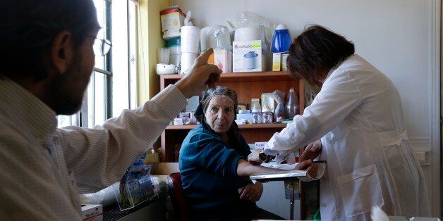 In this photo taken Thursday, Nov. 13, 2014, a doctor gives instructions to an elderly woman as a nurse takes a blood sample at a charity clinic in Athens. Greece's recession - the economyâs shrunk every year since 2008 - was declared over Friday, Nov. 14, 2014. Yet one in every five households has no working member, and a staggering 3 million of Greece's 10.7 million people have lost state health insurance because the long-term unemployed and their dependents lose benefits. (AP Photo/Thanassis Stavrakis)